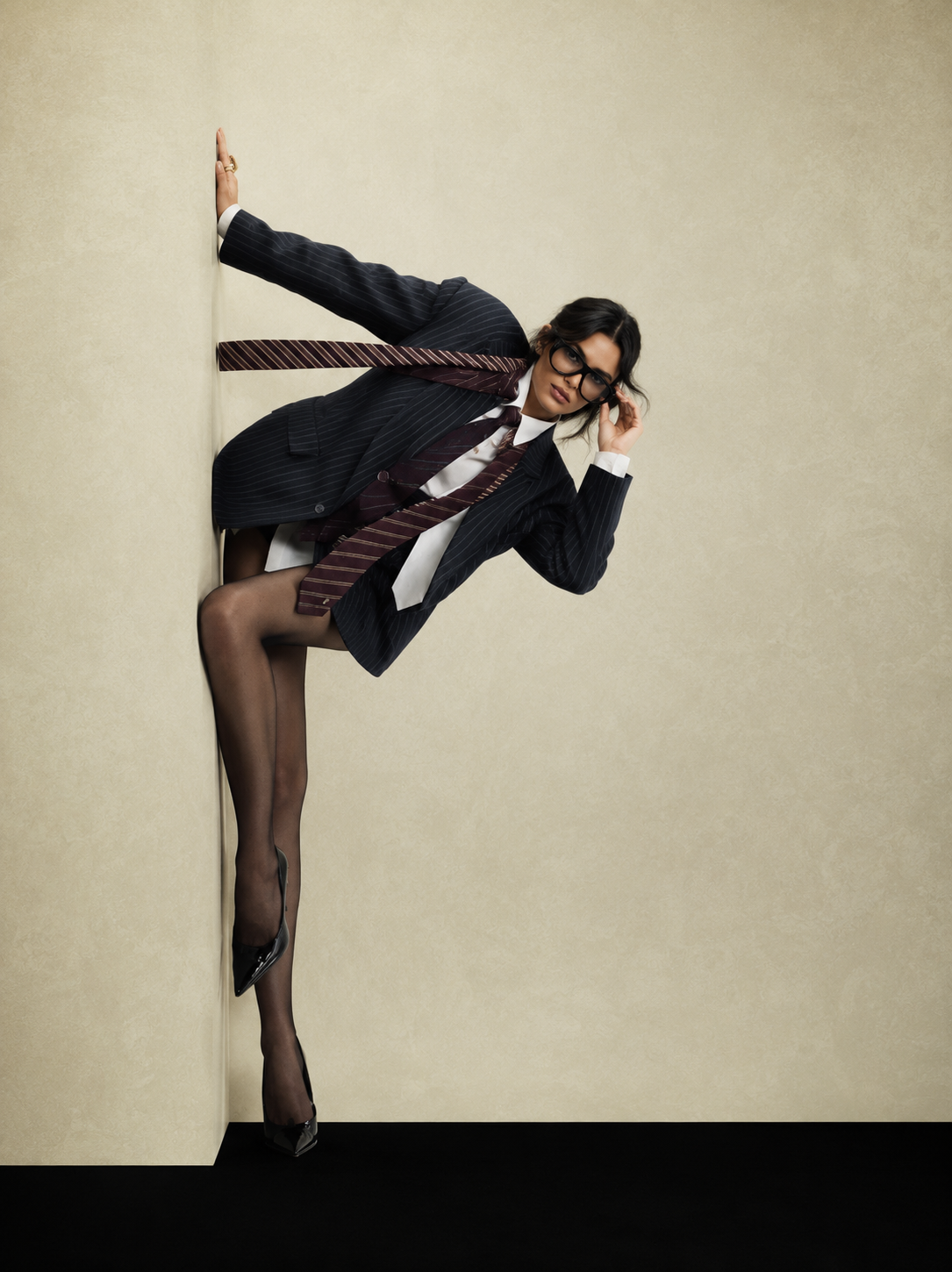 Pinstripe blazer and ties styled as a high kick against a wall
