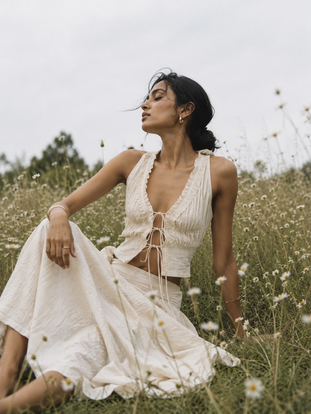 Woman in a cream tie-front set seated in a wildflower field