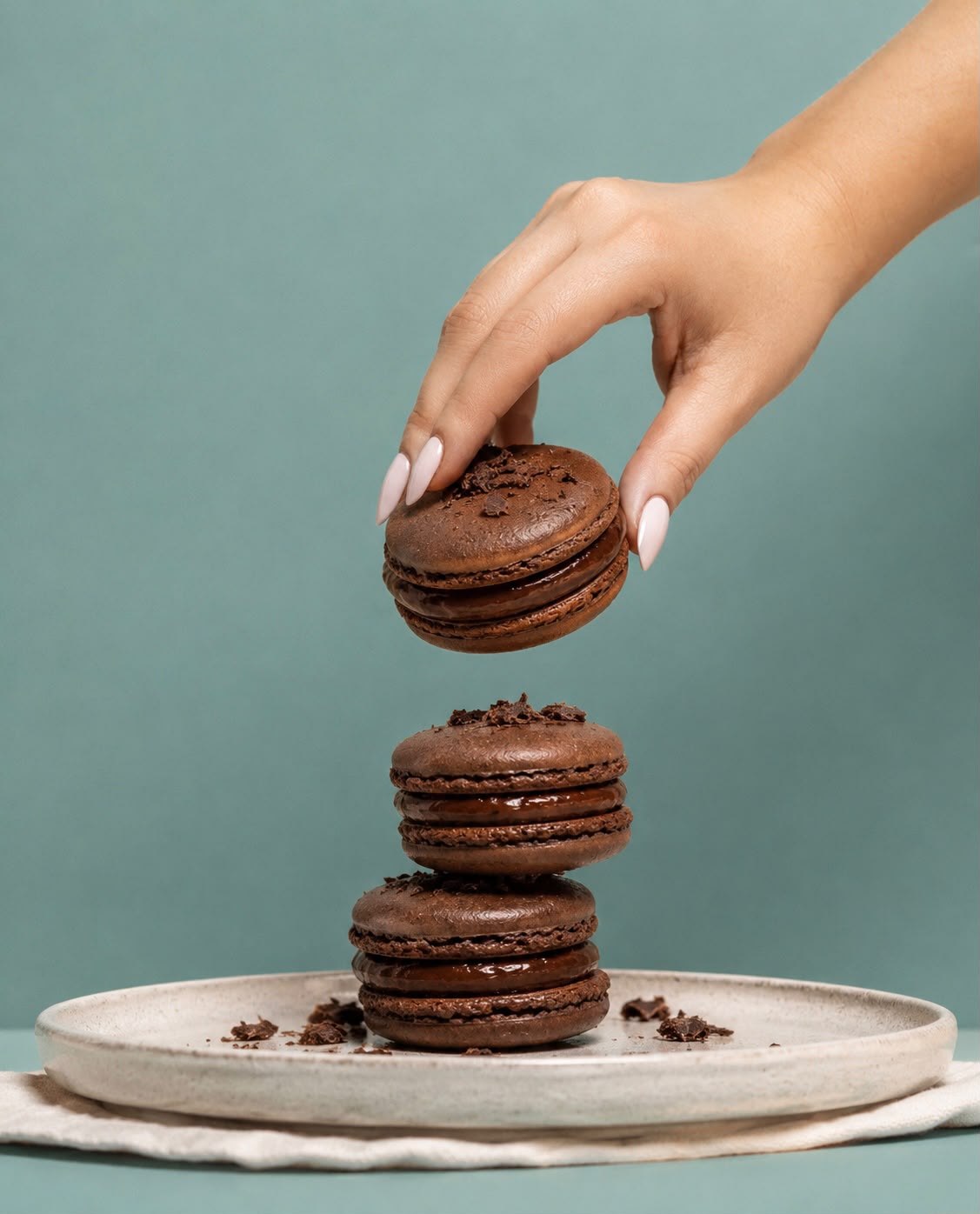 Hand lifting a chocolate macaron