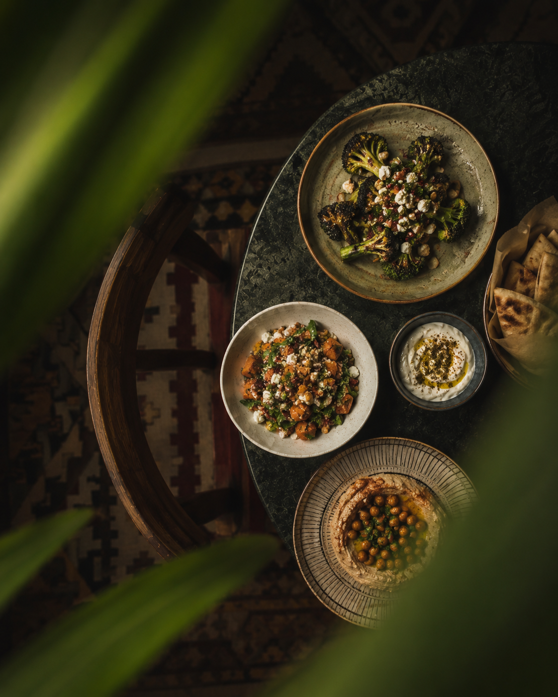 Overhead mezze spread framed through leaves